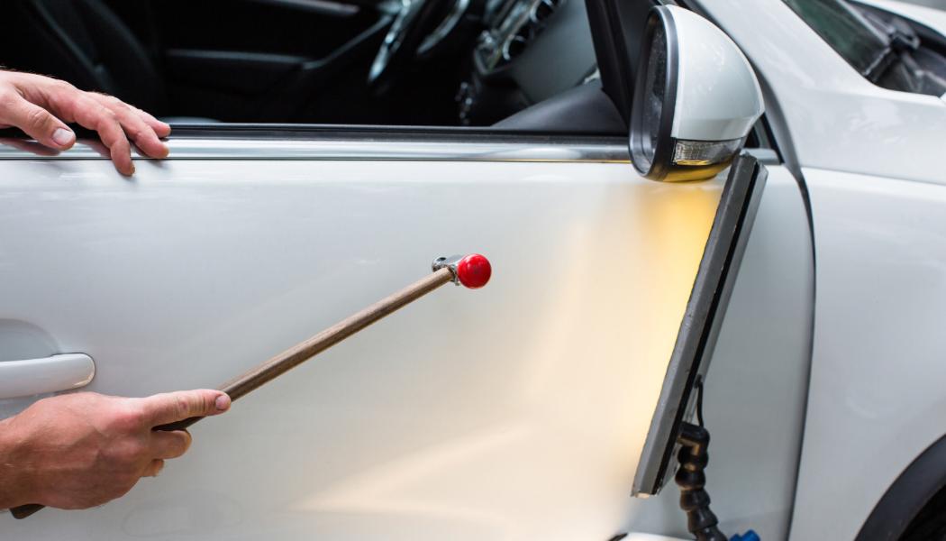 Close-up of a man polishing a car in a garage using an electric buffer tool, showcasing car maintenance.